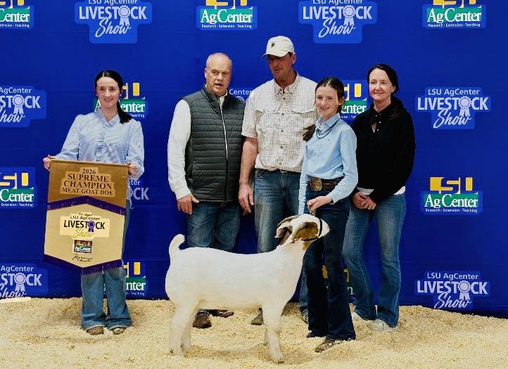A group of people posing with a white goat.